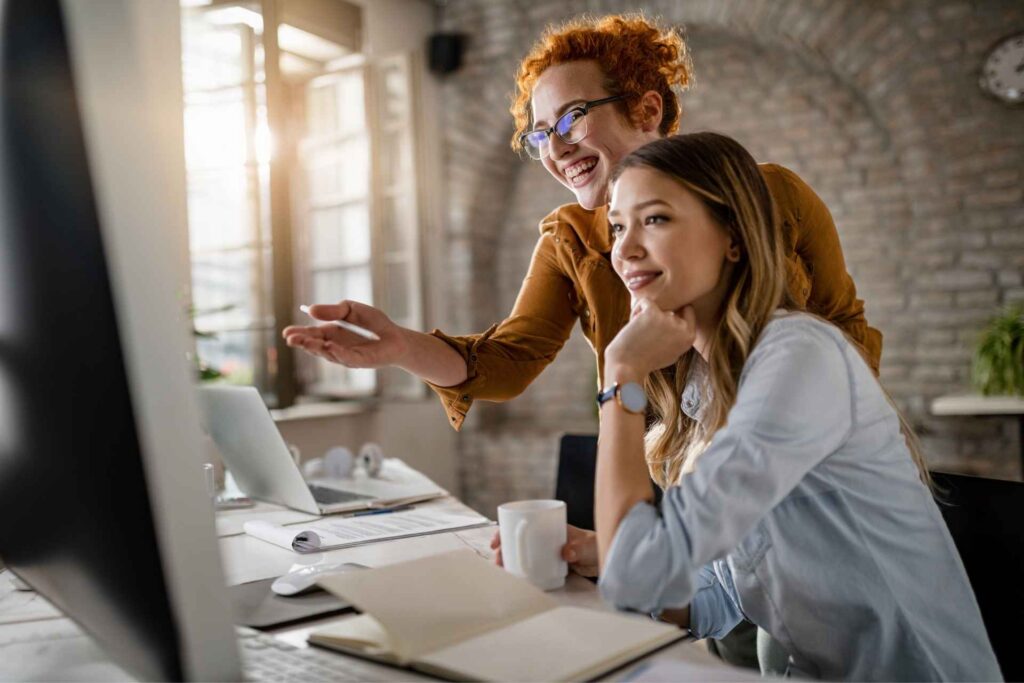 Two marketing professionals collaborating at a computer to review campaign performance and improve treatment center growth.